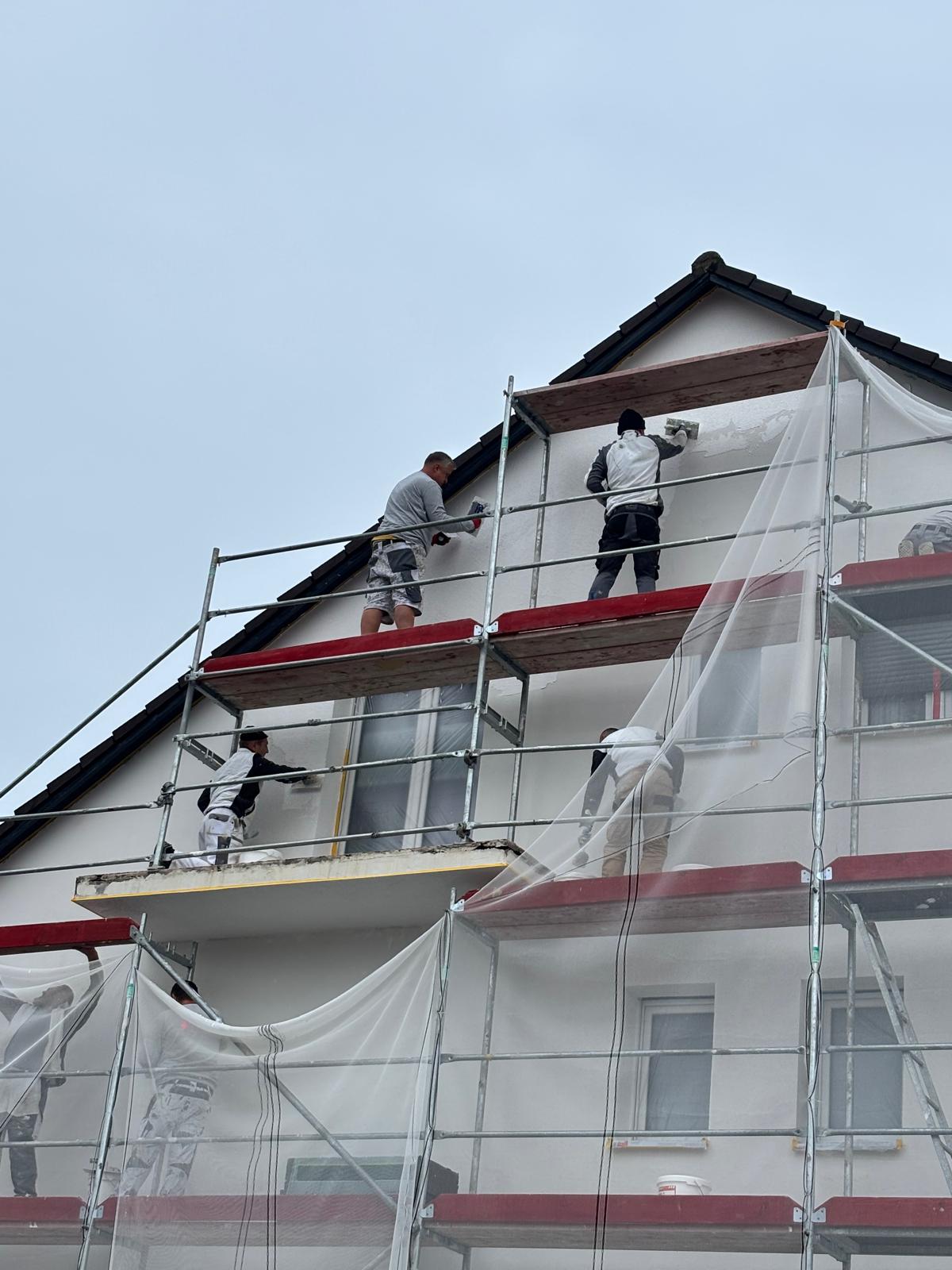 Malerarbeiten an einer Fassade auf dem Gerüst